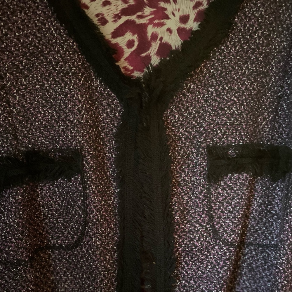Multi color jacket with clasp closure at top. Black fringe around the borders.